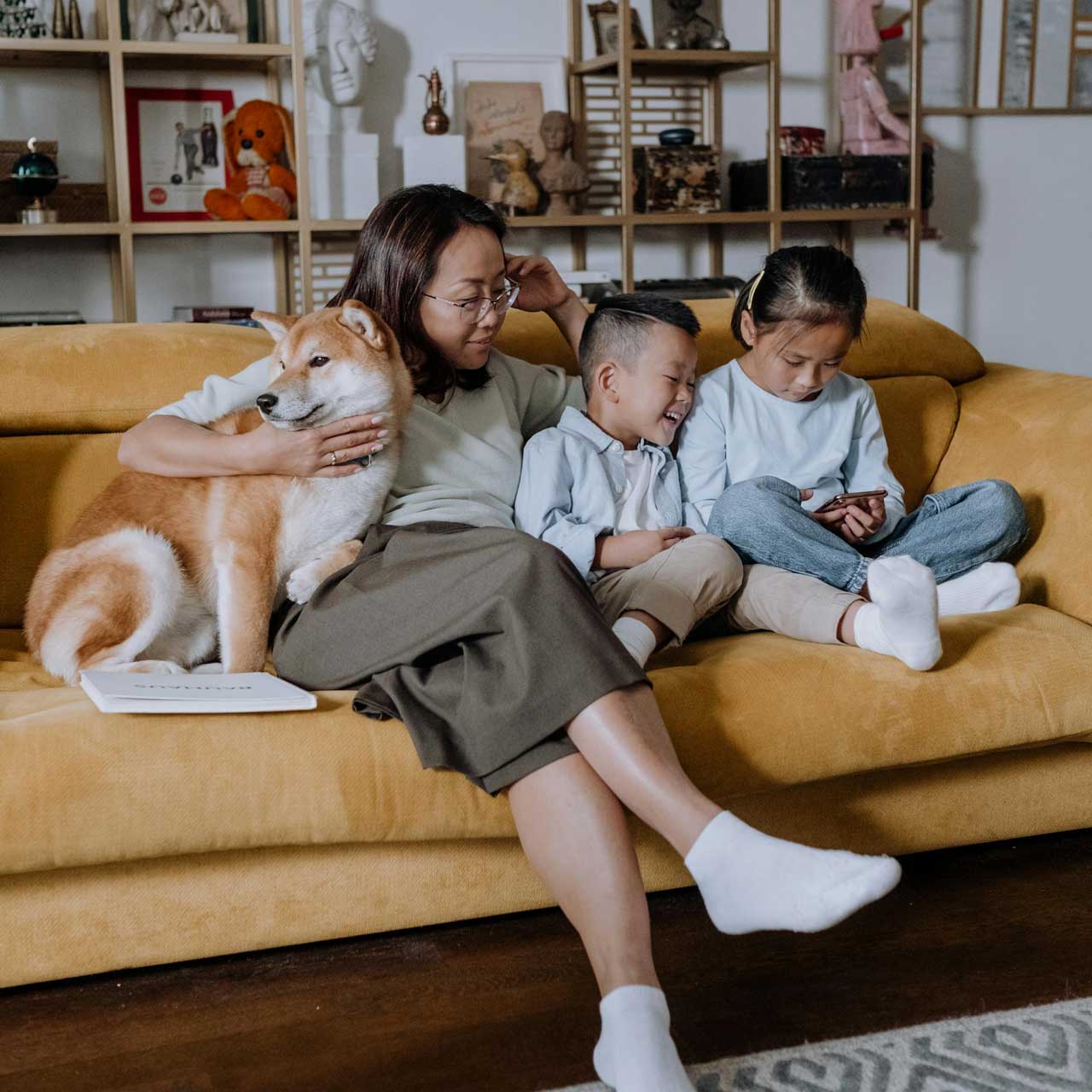 family comfortably sitting on couch looking at smartphone together